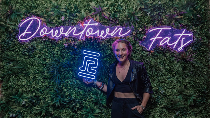 Emily Kenison at Downtown Fats holding a RobeCurls neon sign